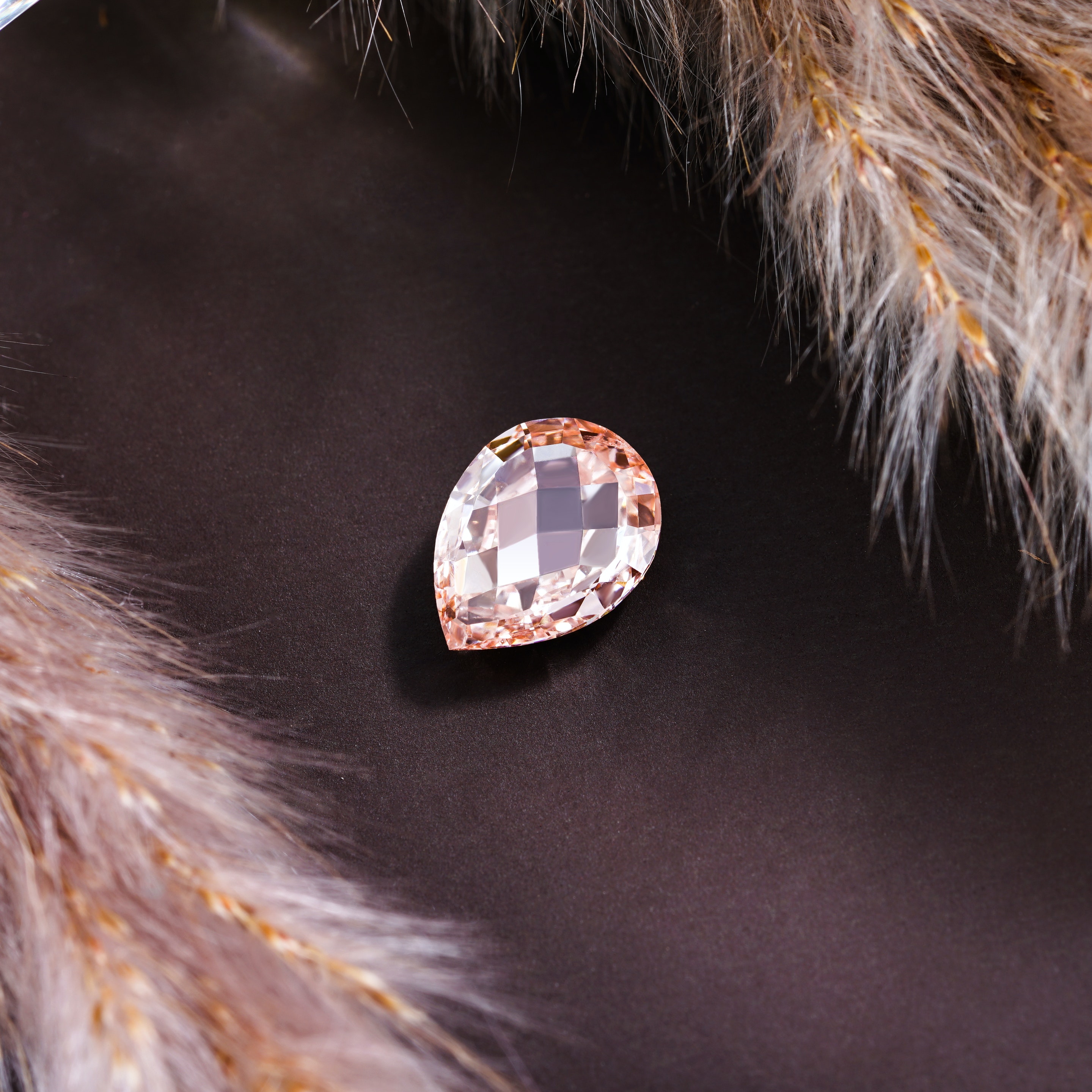 A Pear-shaped diamond still-life surrounded by fur on a black background.