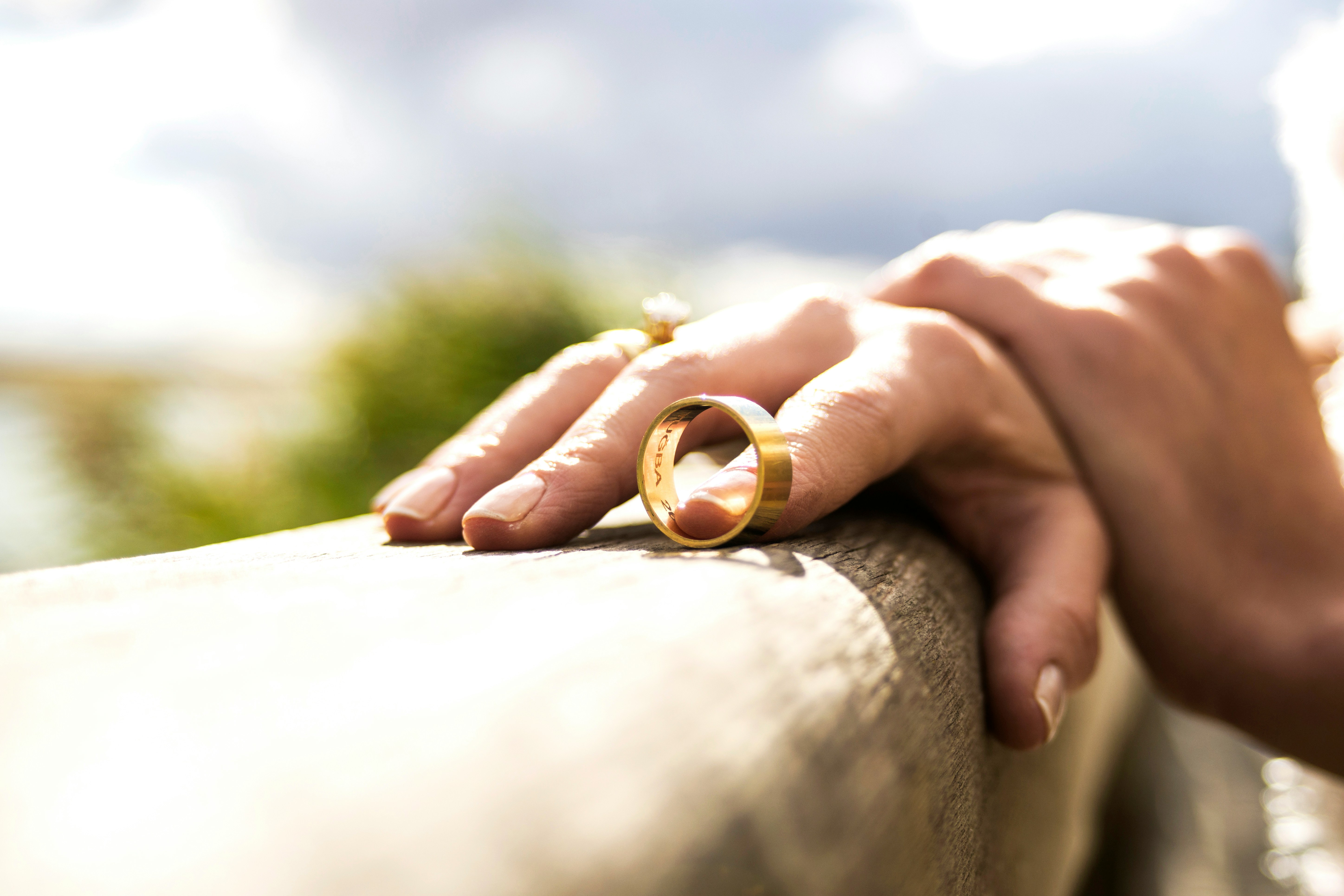 A close-up picture of a hand on a rail, playing idly with a wedding band.
